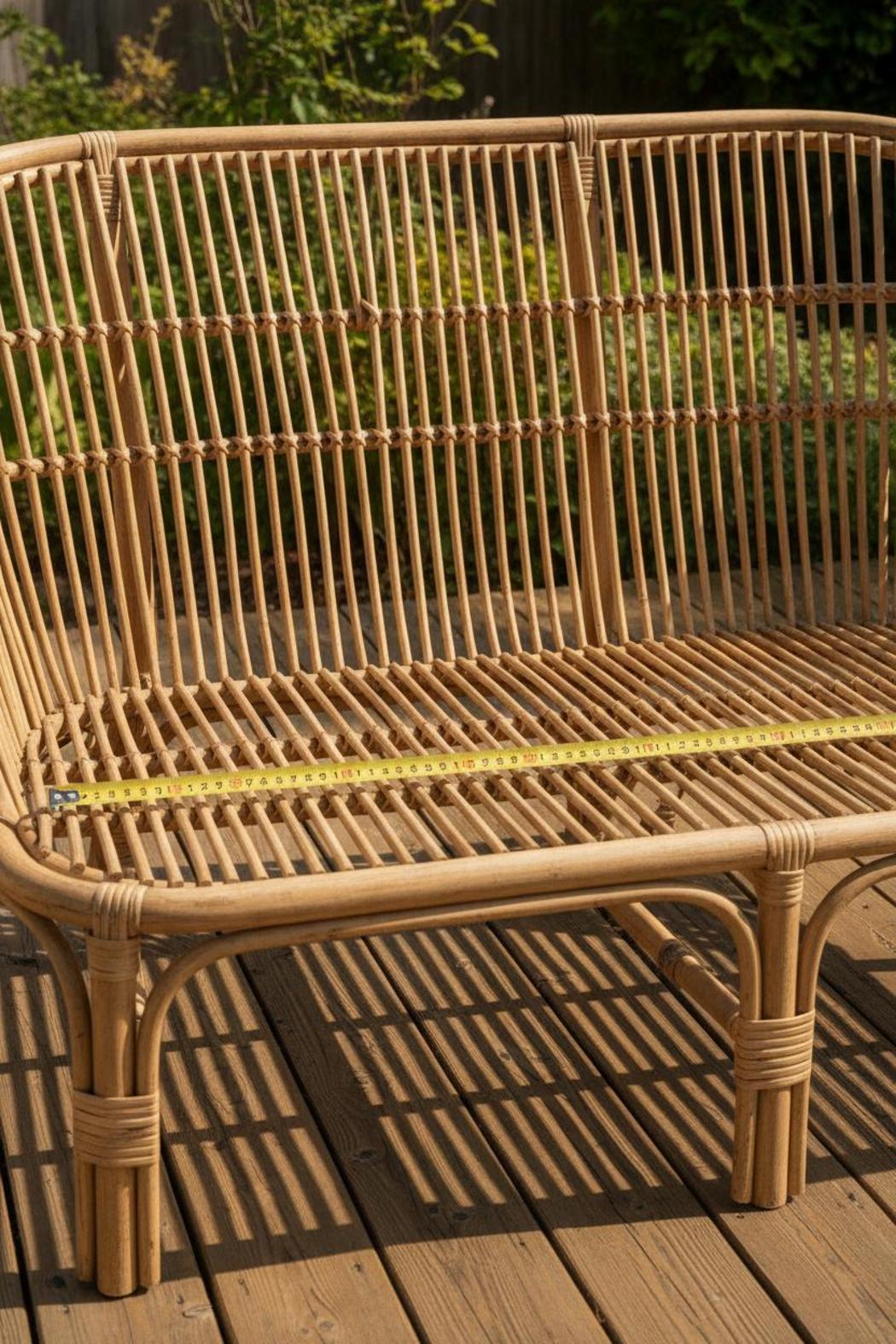 Measuring rattan sofa frame width with tape measure on sunlit deck for rattan furniture cushions replacement set sizing