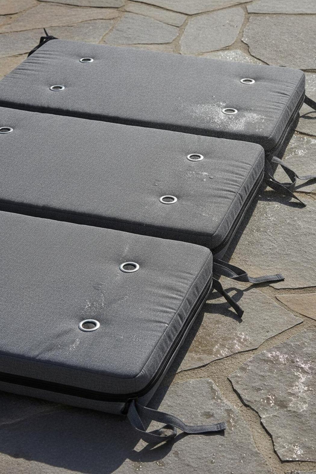 Outdoor seat pads with zippers, tie straps, and drainage holes on stone patio — waterproof outdoor cushions buying guide