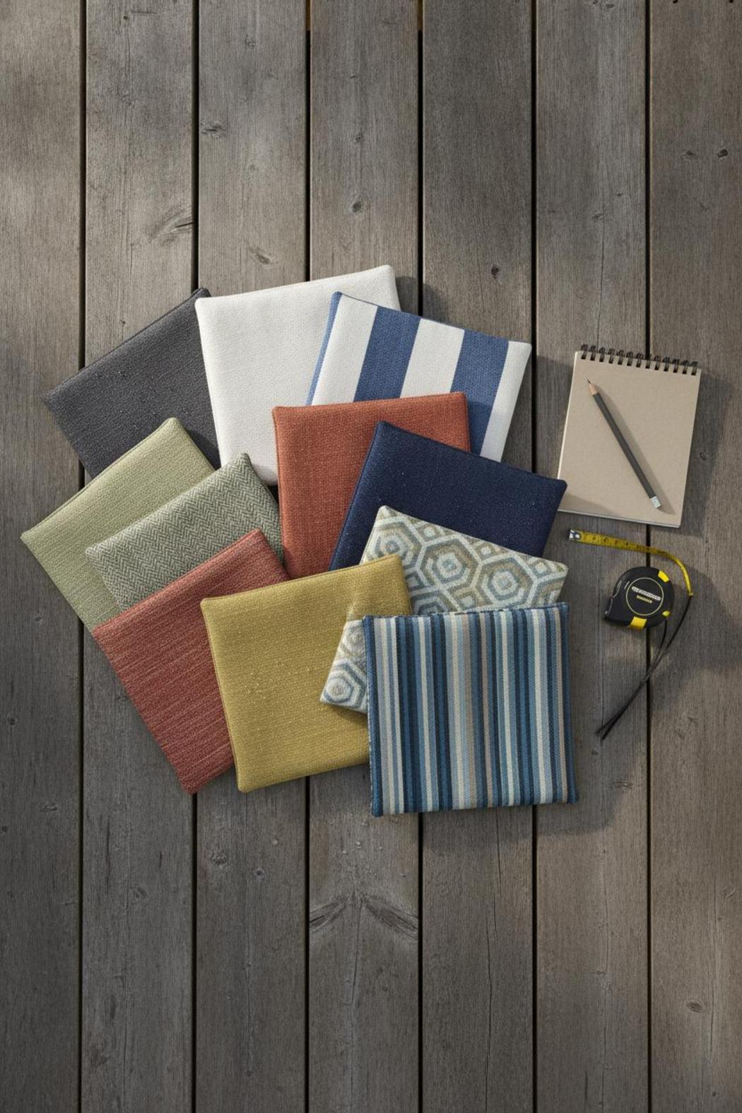 Sunbrella outdoor fabric for patio cushions swatches in various colors on a wooden deck with notebook and measuring tape