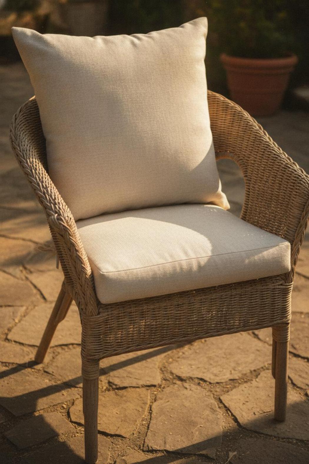 Waterproof cushion for wicker furniture fitting snugly onto open-weave chair seat in warm afternoon patio sunlight
